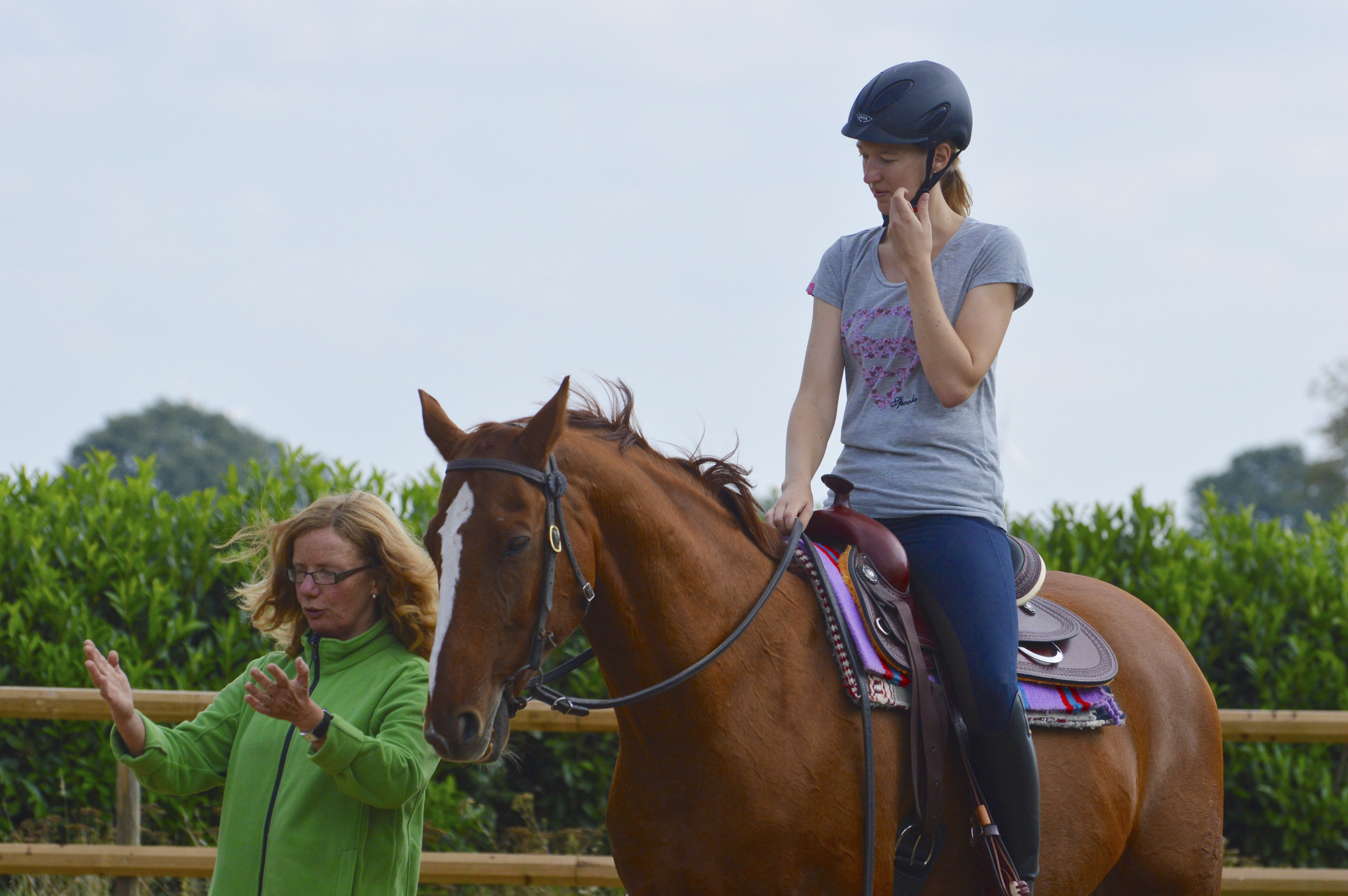 Frau Schöneich erklärt einer jungen Reiterin, die im Westernsattel auf einem Pferd sitzt eine Übung.